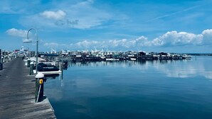 A marina with boats docked, a wooden walkway, and a clear blue sky.