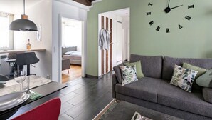 En moderne stue med en grå sofa, et spisebord med stole og et køkkenområde.