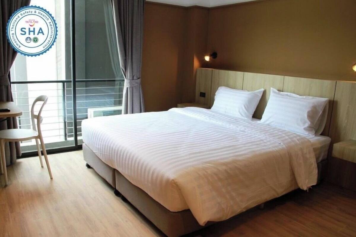 Una camera d'albergo con un letto grande, un comodino, una sedia e una finestra con tende.