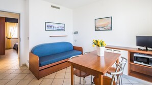 A compact living space with a sofa, a dining table, and a TV. - Classic Appartement in Pietra Ligure (Pietra Ligure)