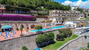 A hotel with a swimming pool, outdoor seating, and a view of the surrounding hills. - Classic Appartement in Pietra Ligure (Pietra Ligure)