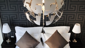 A neatly made bed with white linens and two brown pillows, flanked by two bedside tables with lamps, against a wall with a geometric pattern. - Athens Smart 3-room Private Apartment (Athens)