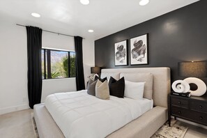 A bedroom with a bed, a nightstand, a lamp, and two framed pictures on the wall. - Designer Luxury  Home w/Pool & Hot Tub Foothills (Tucson)