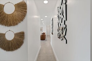 Un couloir au design moderne, agrémenté d’œuvres d’art abstraites accrochées au mur et d’une décoration murale tissée.