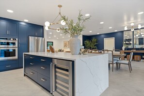 Une cuisine moderne avec des meubles de couleur bleu foncé, des appareils en acier inoxydable et un îlot central en marbre.