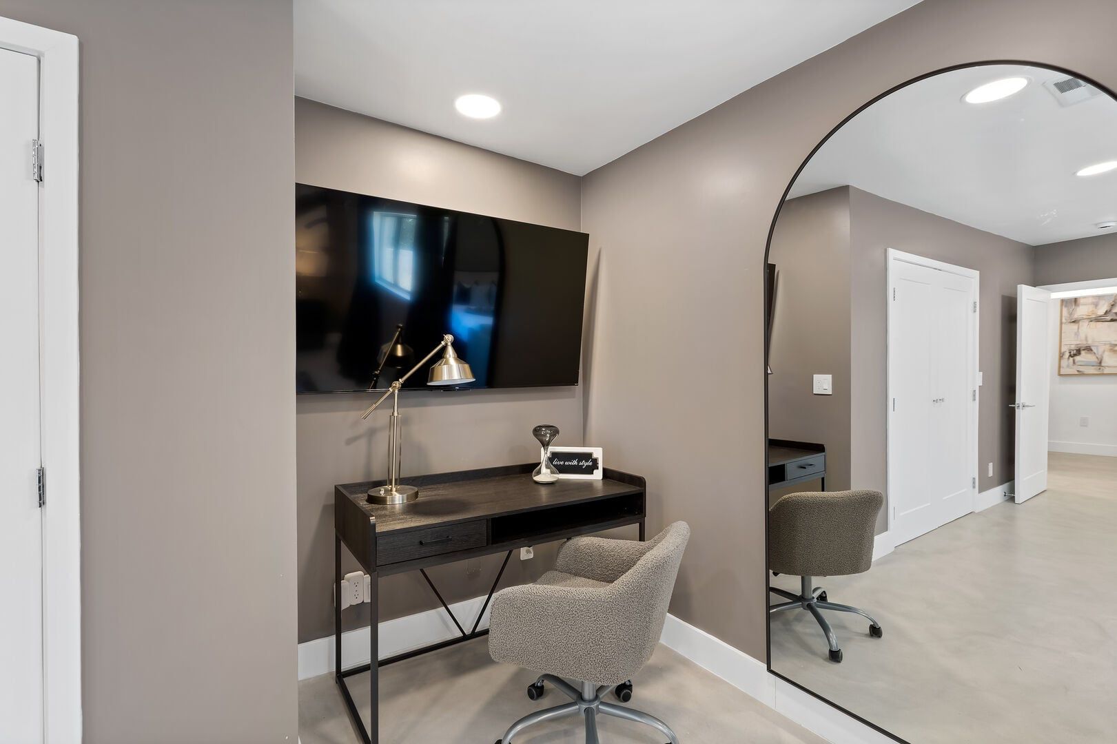 A modern office space with a desk, chair, and a large mirror.