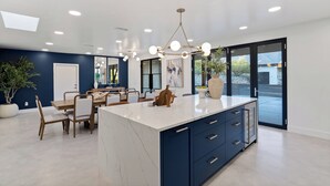 A modern kitchen with a large island, dark blue cabinetry, and a pendant light fixture.