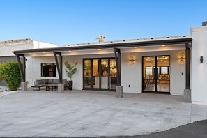 A modern building with a covered patio area, large sliding glass doors, and outdoor seating.
