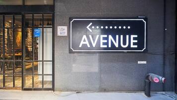 Una señal de calle que indica 'AVENUE' con una flecha apuntando a la izquierda, un letrero que dice 'BEST' y un hidrante en la acera.