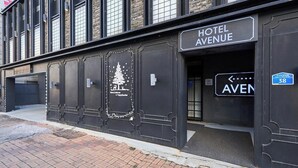 A building with a sign reading "HOTEL AVENUE" and a directional sign pointing left. - AVENUE HOTEL (Osan)
