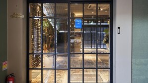 A hotel entrance with a glass door, a fire extinguisher, and a 'Merry Christmas' sign. - AVENUE HOTEL (Osan)
