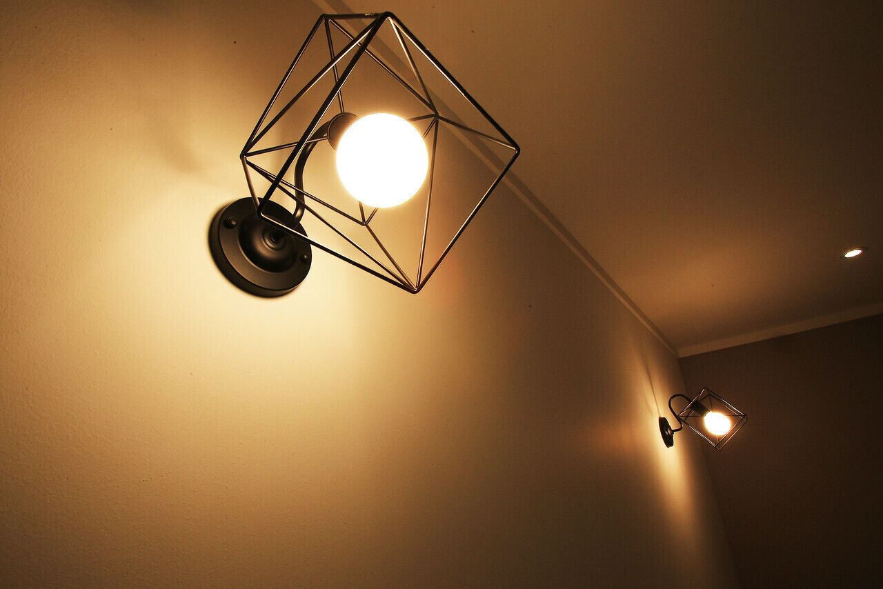 A geometric wall-mounted light fixture with a round bulb.