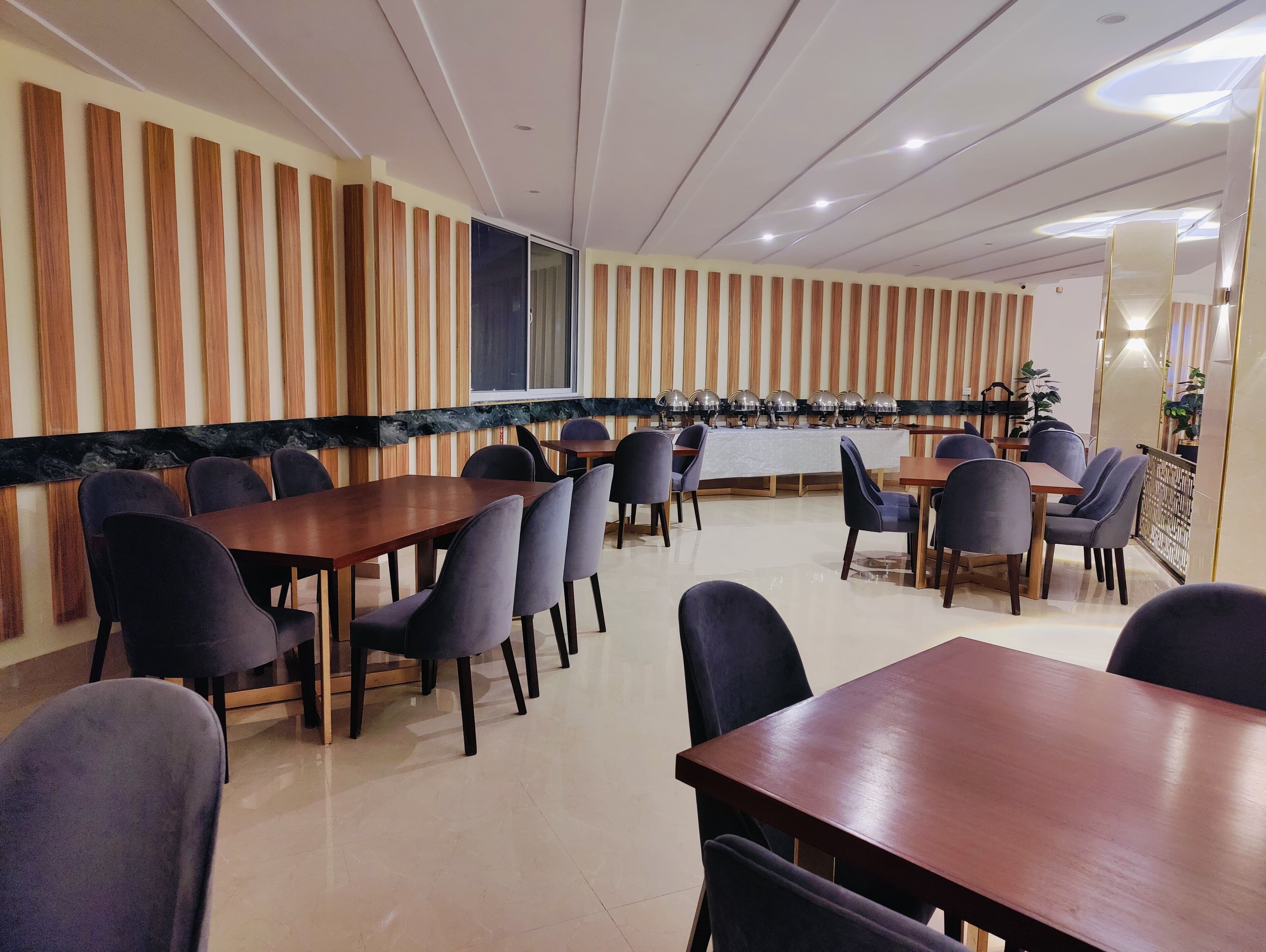 Une salle de conférence aux murs lambrissés, avec un mur d’accent en marbre et une table centrale entourée de chaises.