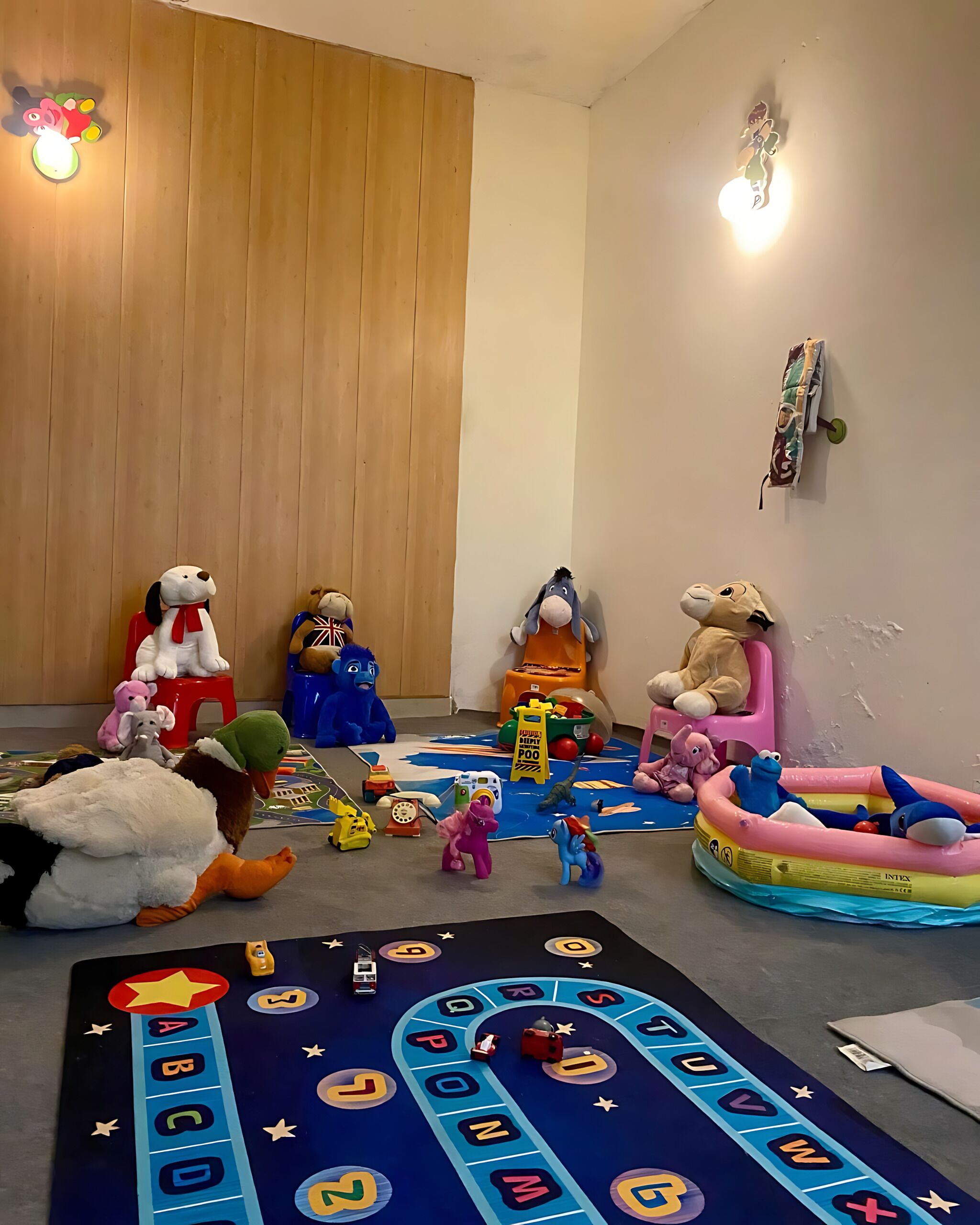 A playroom with a mat game, stuffed animals, and toys.