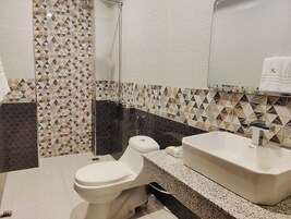 A bathroom with a toilet, sink, and shower. The walls have a geometric tile pattern.