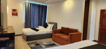 Um quarto com cama, sofá, tapete, porta de madeira e uma obra de arte pendurada na parede.