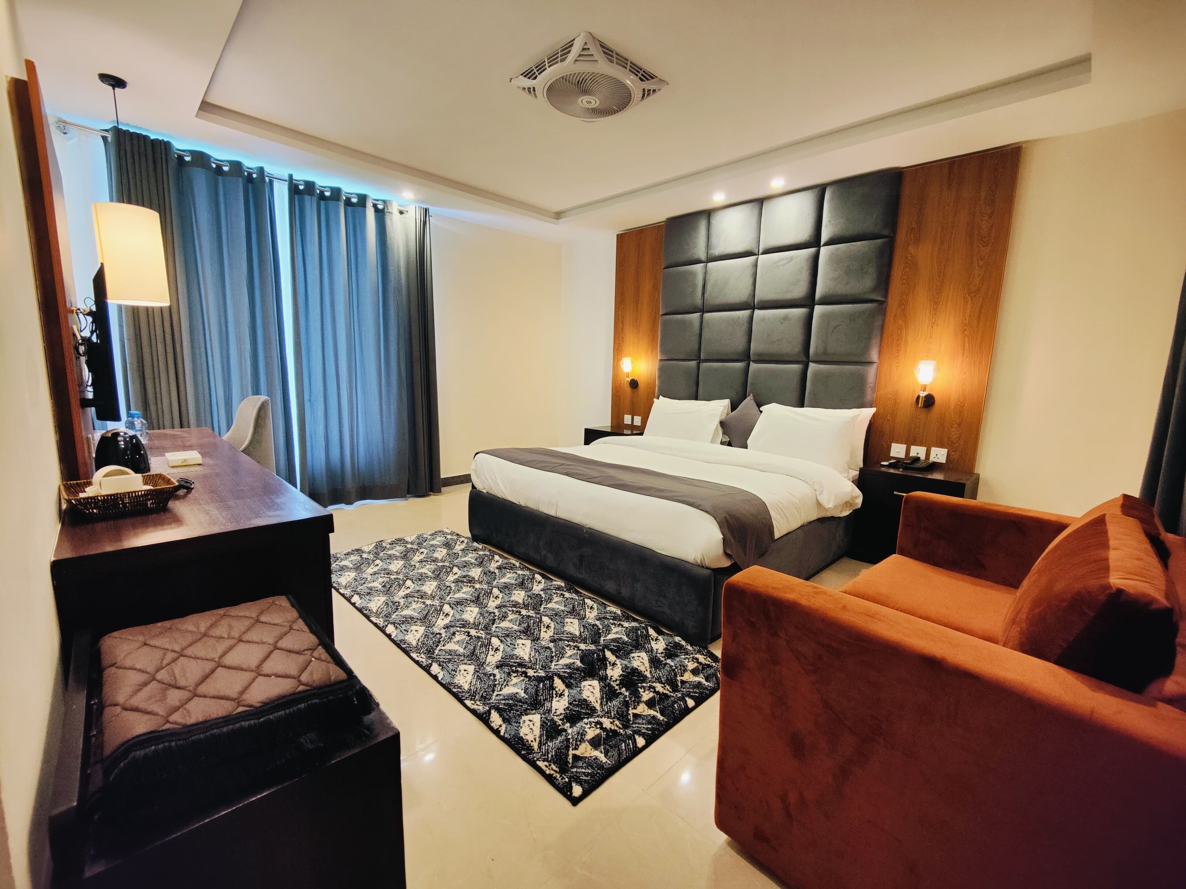 Ein modernes Hotelzimmer mit einem großen Bett, einem Schreibtisch, einem Sessel und einer Couch.