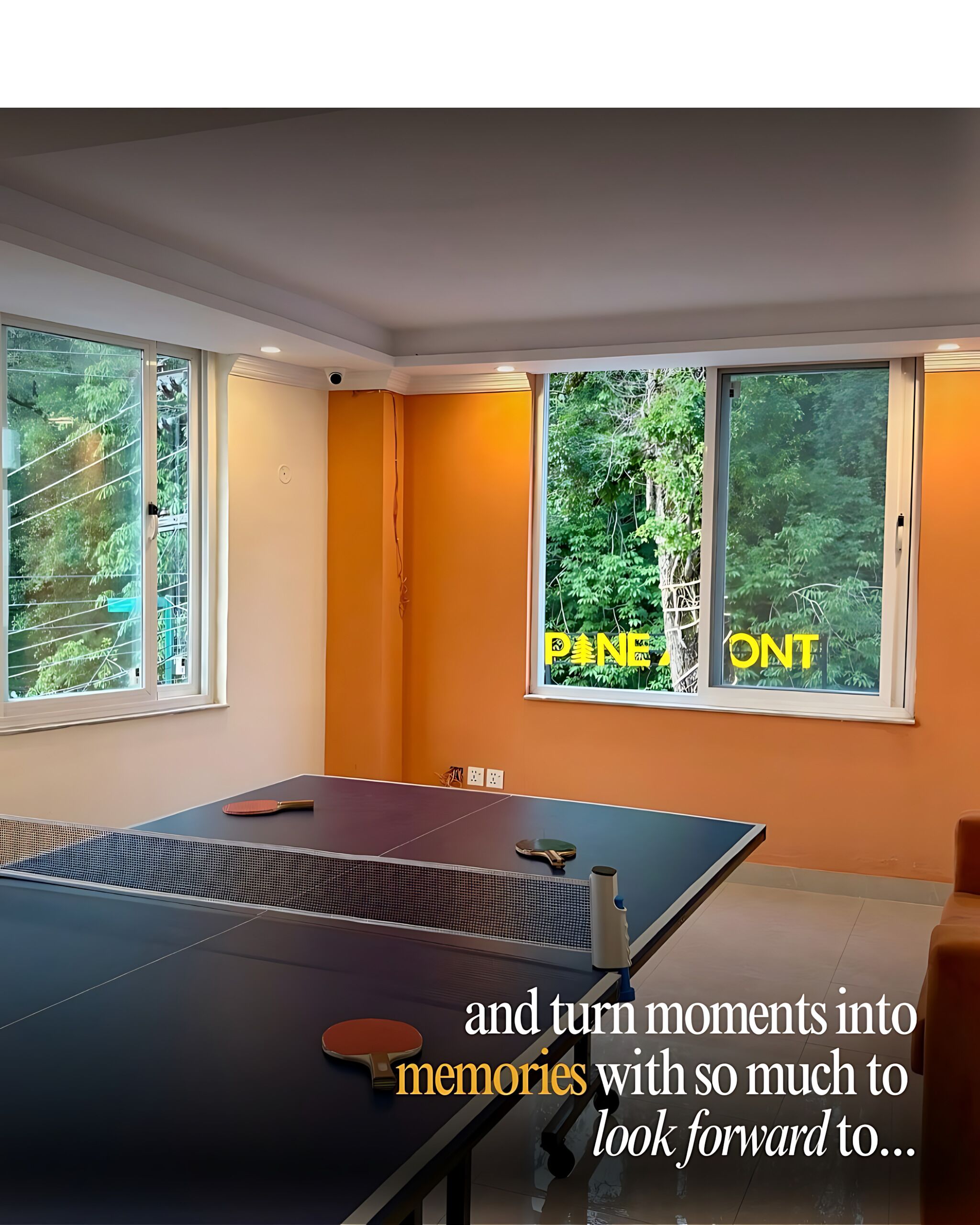 A room with a ping pong table, large windows with a view of trees, and a text overlay.