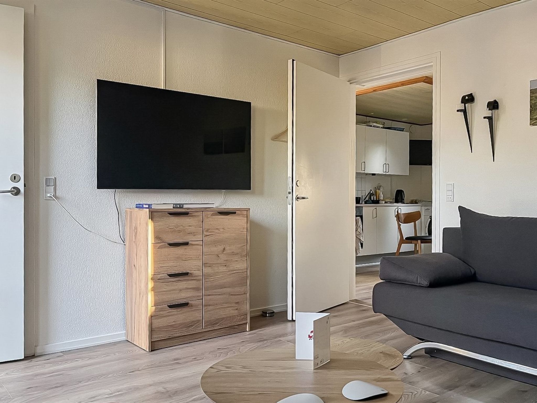 Un soggiorno moderno con una televisione a schermo piatto, un mobiletto in legno, un divano grigio e un tavolino.