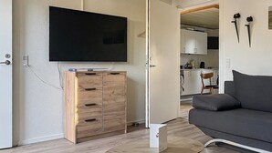 Un salon moderne avec un téléviseur à écran plat, un meuble en bois, un canapé gris et une table basse.