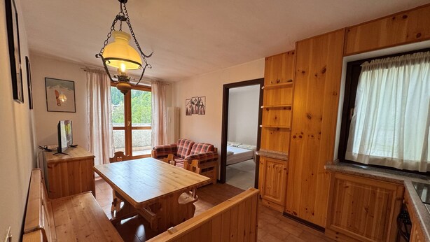 A wooden interior with a dining table, a sofa, and a kitchen area.