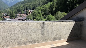 A balcony with a view of a mountainous area and houses.