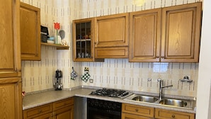 A kitchen with wooden cabinets, a gas stove, a sink, and a dishwasher. - 020 Trilocale Pinzolo (Pinzolo)