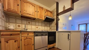 Eine Küche mit Holzschränken, einem Geschirrspüler, einem Backofen und einem Kühlschrank.
