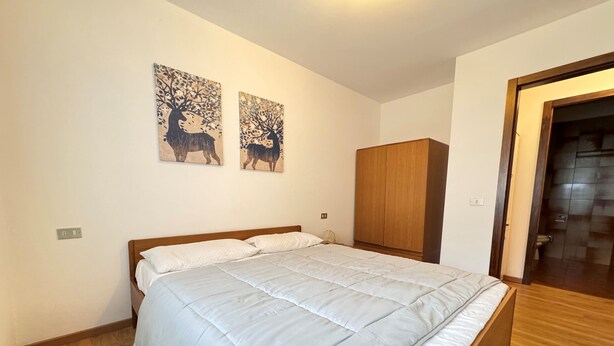 Ein Schlafzimmer mit Bett, zwei an der Wand befestigten Bildern, einem Kleiderschrank und einer Badezimmertür.
