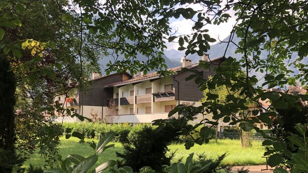 A two-story building with a balcony, surrounded by greenery and a clear sky. - 040 Bilocale Pinzolo (Pinzolo)