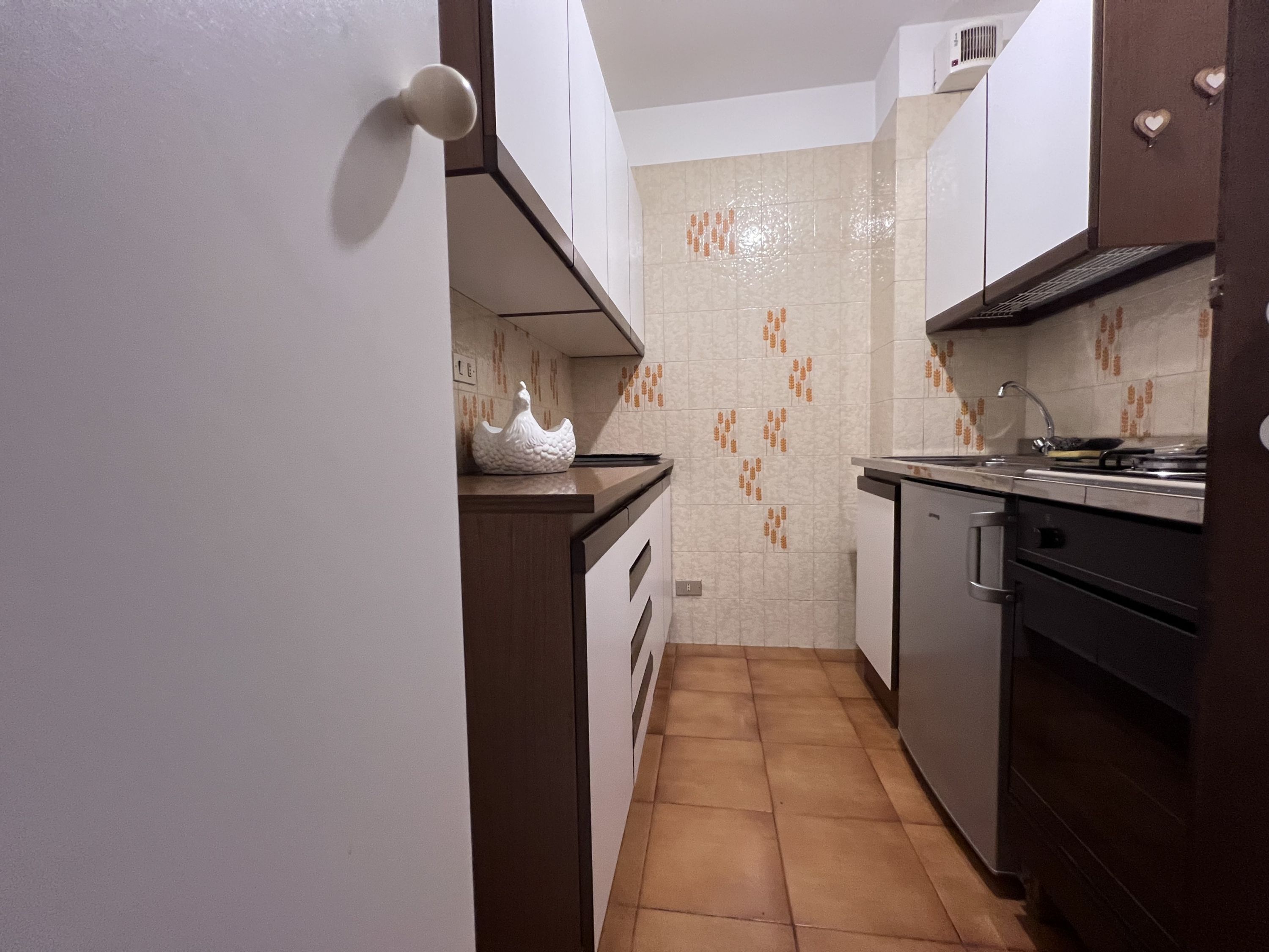 A compact kitchen with a tiled backsplash, a sink, and a stove.