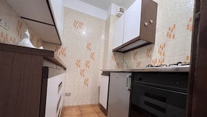 A compact kitchen with a refrigerator, oven, and a stove. - 040 Bilocale Pinzolo (Pinzolo)