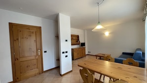 A compact living space with a dining area, a kitchenette, and a seating area. - 090 Cond Gaiolin 22 (Giustino)