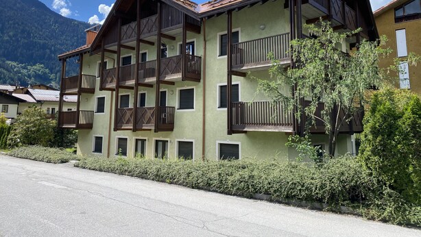 A multi-story building with balconies and a mountain backdrop. - 090 Cond Gaiolin 22 (Giustino)