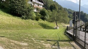 Un área con césped, un sendero empedrado, una cerca y un edificio al fondo.