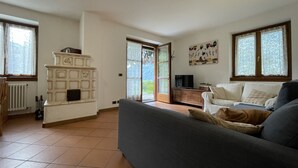 A living room with a fireplace, a sofa, a television, and a view through a glass door.
