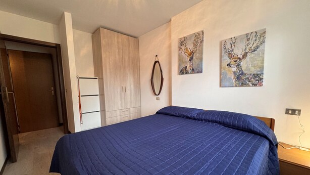 Una camera da letto con un letto grande, un armadio, una porta e due quadri appesi al muro.