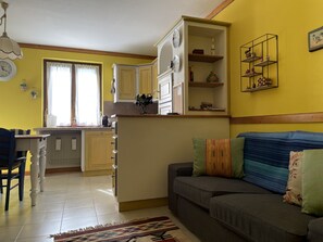 A cozy living room with a sofa, a coffee table, and a dining area with a table and chairs. - 072 Trilocale Giustino (Giustino)