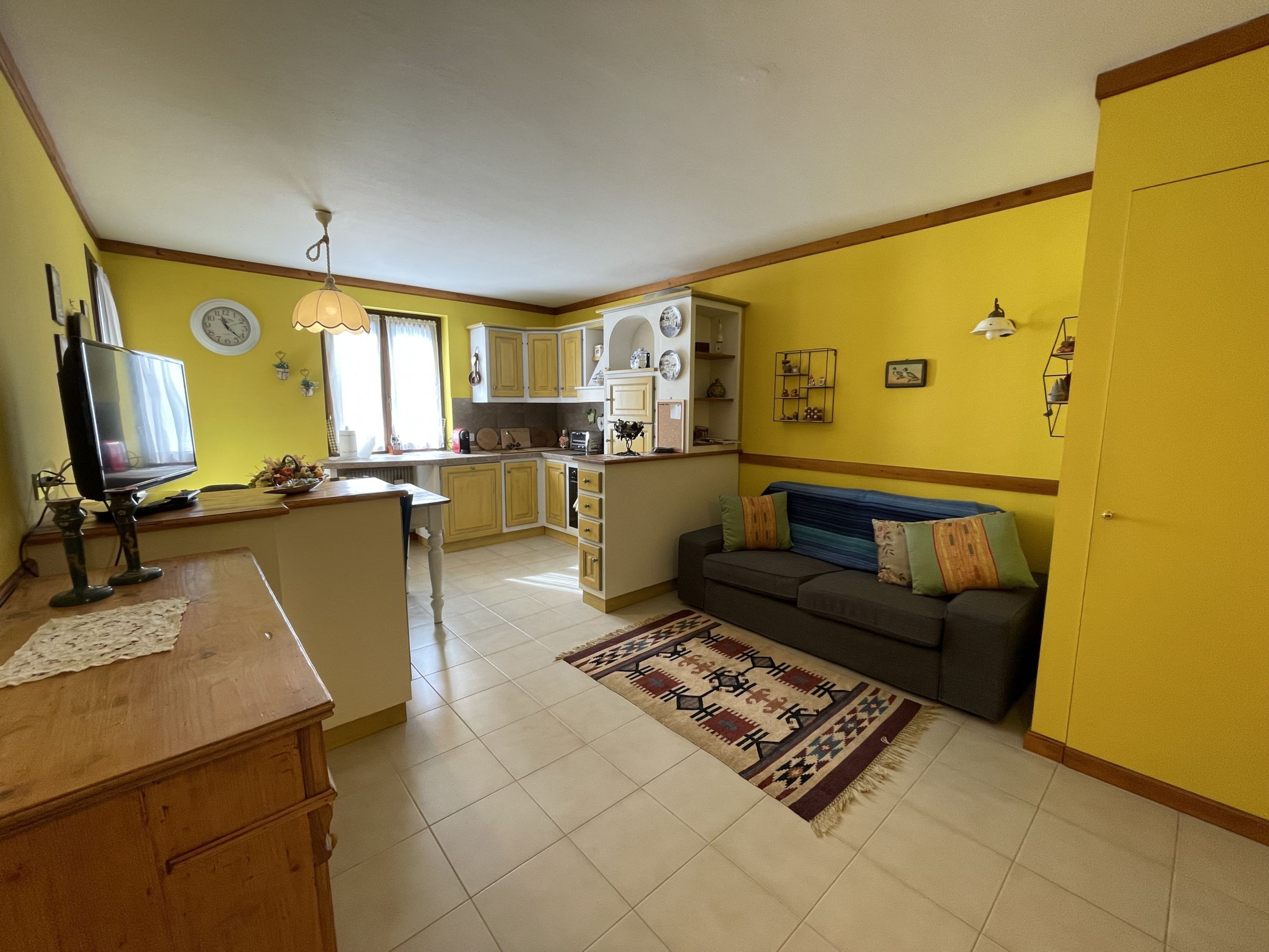 Ett kompakt bostadsutrymme med kök, matplats och en soffa.