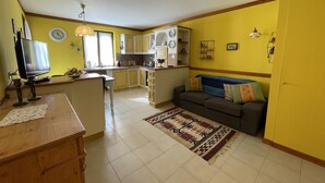 A compact living space with a kitchen, dining area, and a sofa. - 072 Trilocale Giustino (Giustino)
