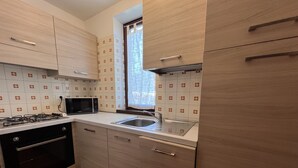 Una cocina moderna con armarios de madera clara, un lavamanos de acero inoxidable y una estufa a gas.