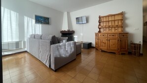 Una sala de estar con un sofá gris, un mueble de madera, un televisor de pantalla plana y un cuadro en la pared.