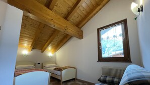 A bedroom with a checkered floor, a bed, a small table, and a window with a view of a mountain. - 032 Luminosa Mansarda Pinzolo (Pinzolo)