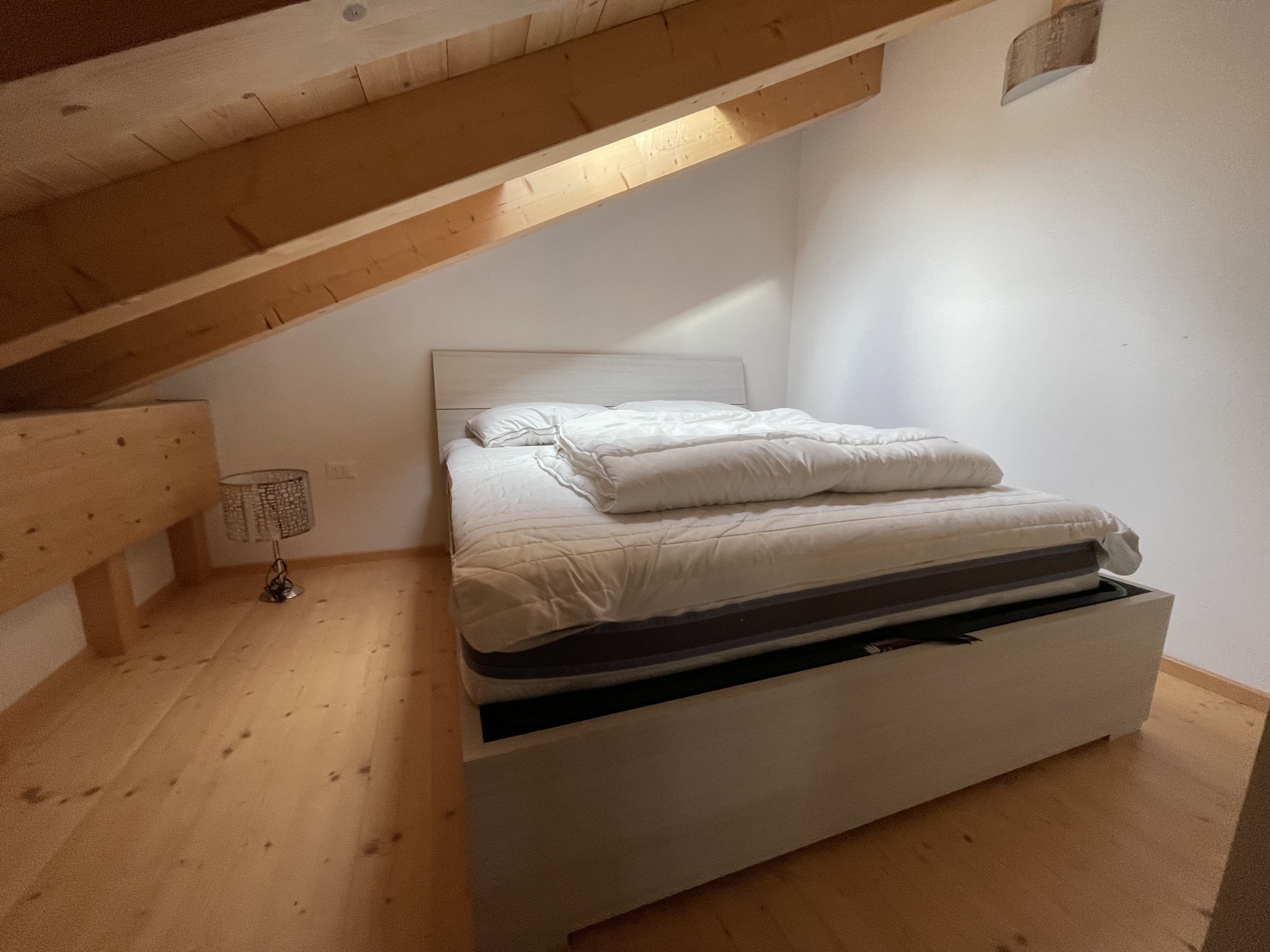 Un dormitorio con cama, mesita de noche y una lámpara de mesa.