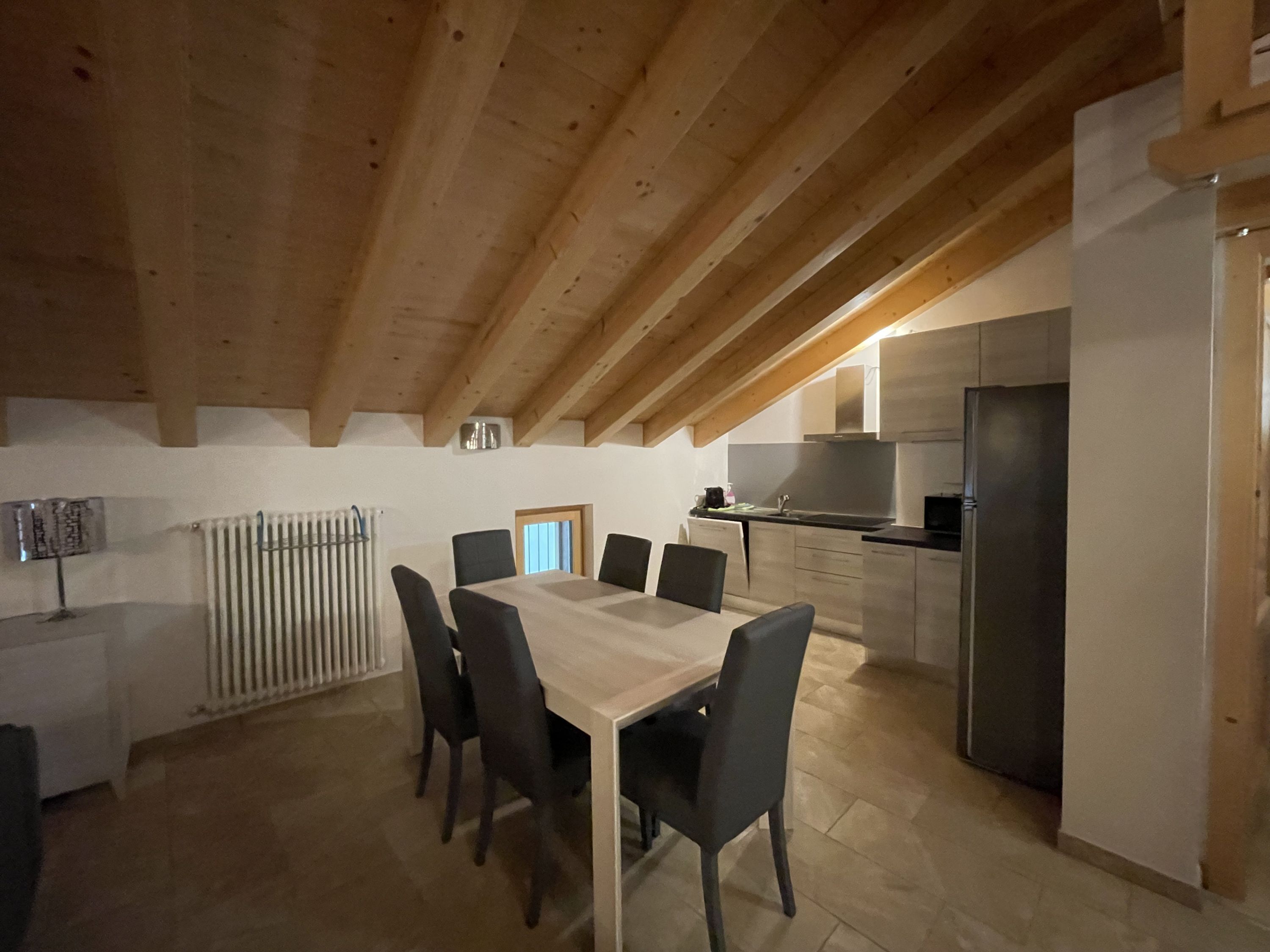 Une cuisine moderne dotée d’un îlot central, d’un coin repas avec une table et des chaises en bois, et d’une fenêtre bien visible.