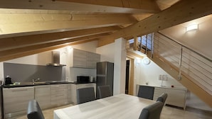A modern kitchen with a dining area, wooden beams, and a staircase. - 061 Bilocale Mansarda Carisolo (Carisolo)