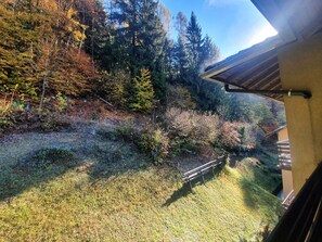 A view from a balcony overlooking a forested area with a wooden bench and a metal railing. - 026 Bilocale con Caminetto Giustino (Giustino)