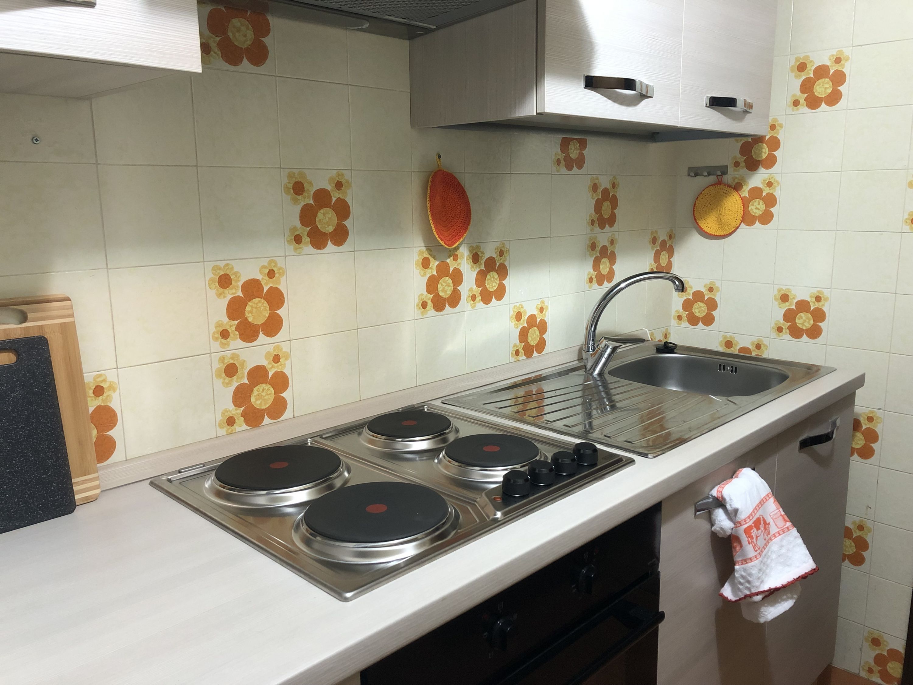 Een keuken met een fornuis, spoelbak en kasten.