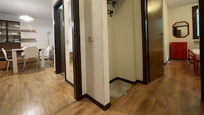 A modern interior with a wooden floor, a dining area with white chairs, and a red cabinet.