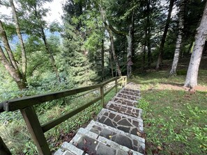 A stone staircase with a wooden handrail leading up a forested path. - 048 Trilocale Duplex nel Verde Pinzolo (Pinzolo)